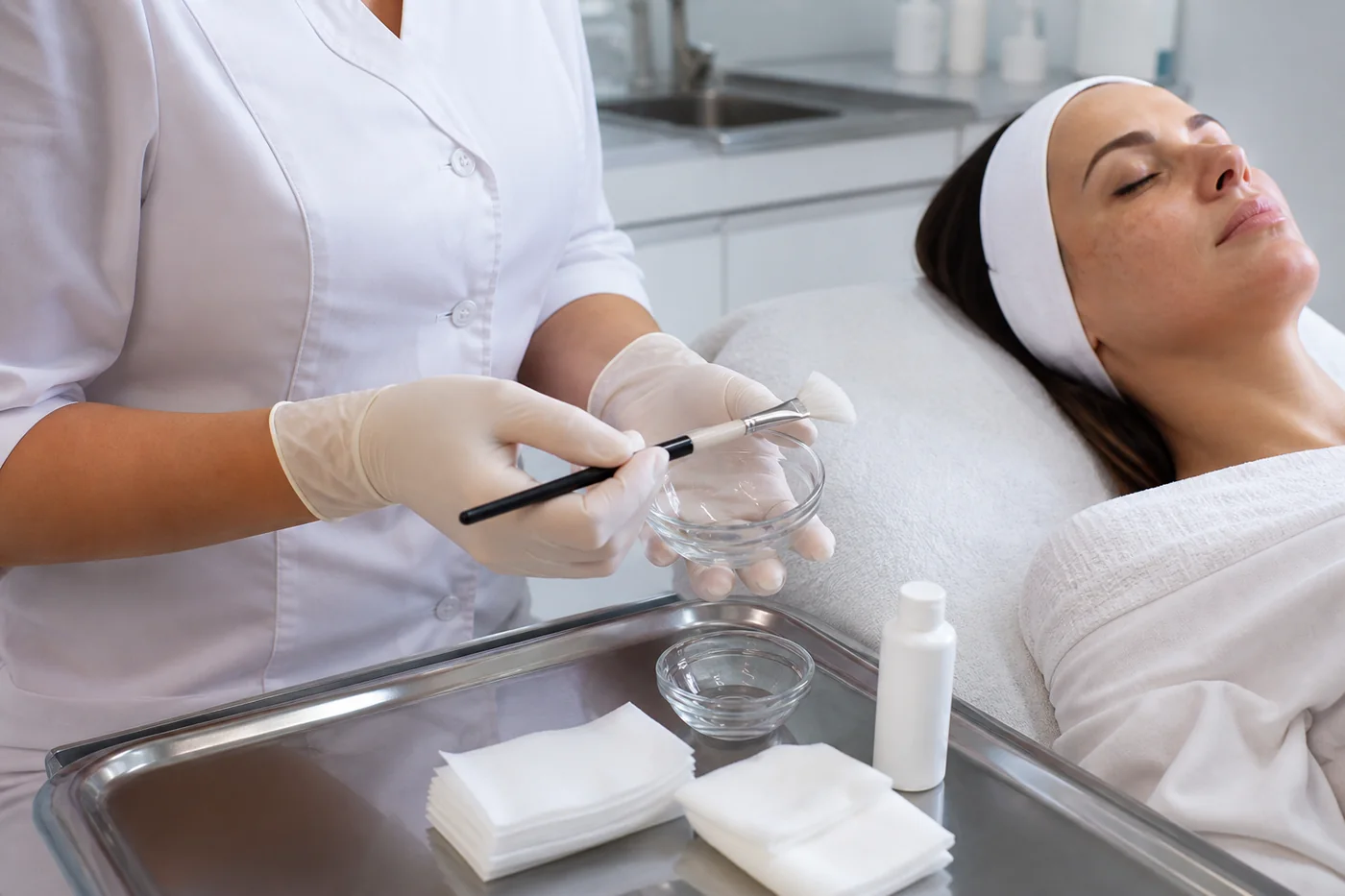 Kosmetyczka w rękawiczkach przygotowuje peeling chemiczny po ocenie przebarwień skóry